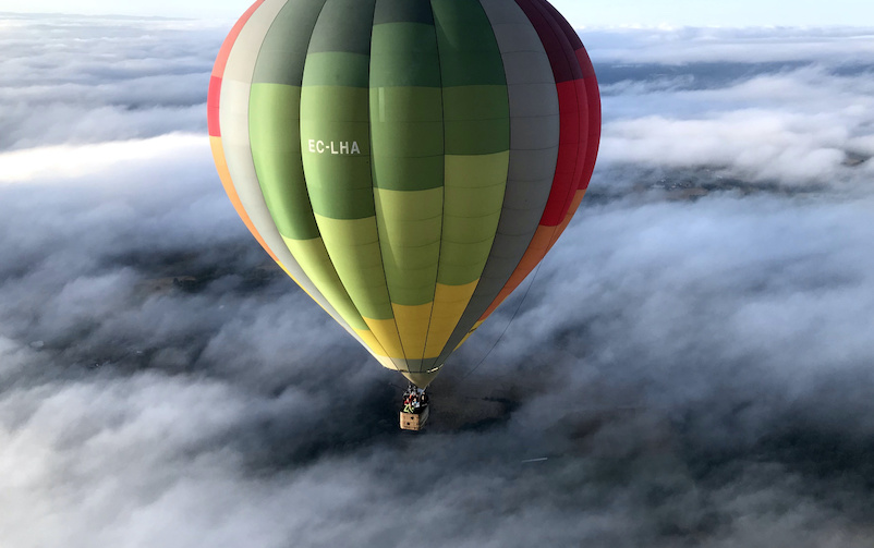 Globo aerostático sobre un paisaje cubierto de niebla