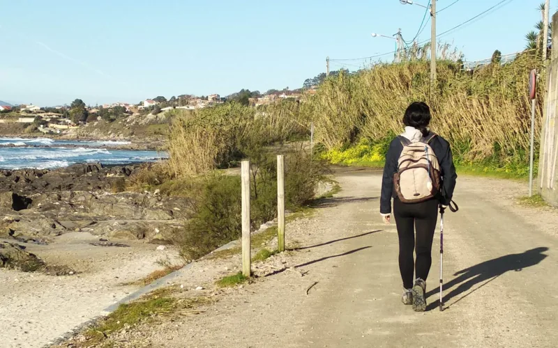 Persona caminando con mochila junto a la costa