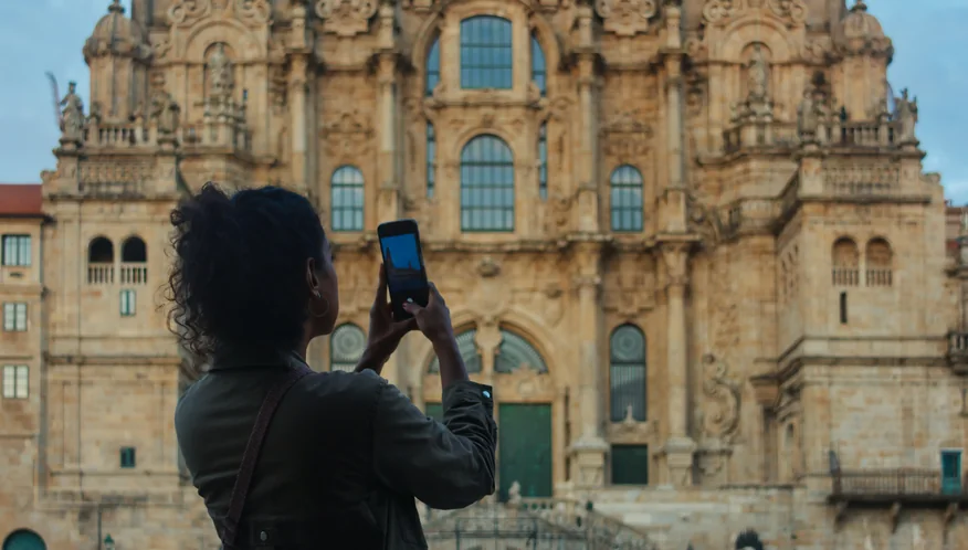 Viajera fotografiando la catedral de Santiago de Compostela con un teléfono Viajera fotografiando la catedral de Santiago de Compostela con un teléfono